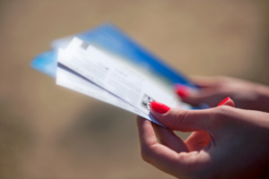 A woman with bright red nails fans out a stack of event tickets she got using her company’s flexible ticketing fund.